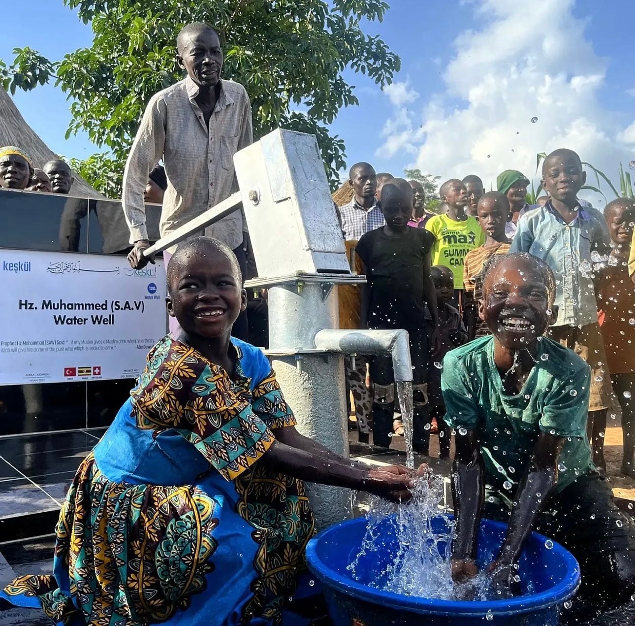 Uganda'da açılan su kuyusundan temiz su alan çocuklar